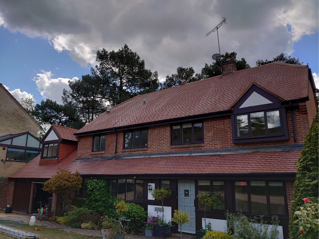 Recently soft washed red tiled home with black gutters and red brick walls