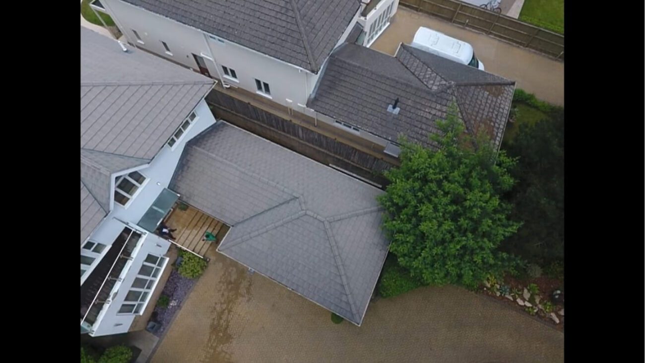 Garden structure with grey roof tiles recently soft washed adjacent to dirty home