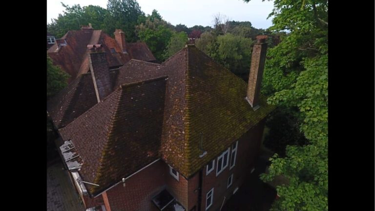 Side on view of a moss coated red tiled roof in residential Dorset