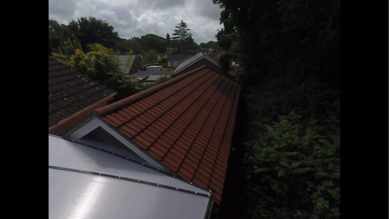 Treeline view of recently cleaned garden building rood with red tiles
