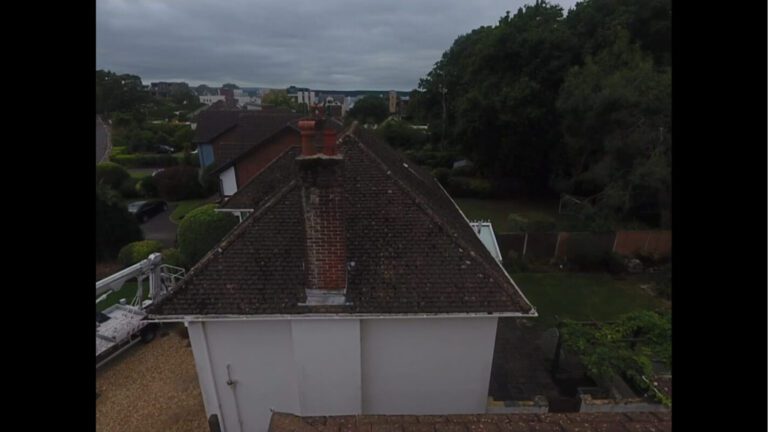 white home with dark tiled roof covered in moss