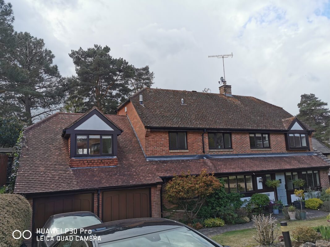 Red bricked wide home with red tiled roof dirty with moss