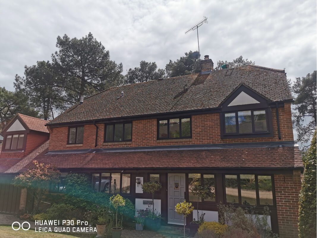 Red brick home with filthy roof in need of soft wash