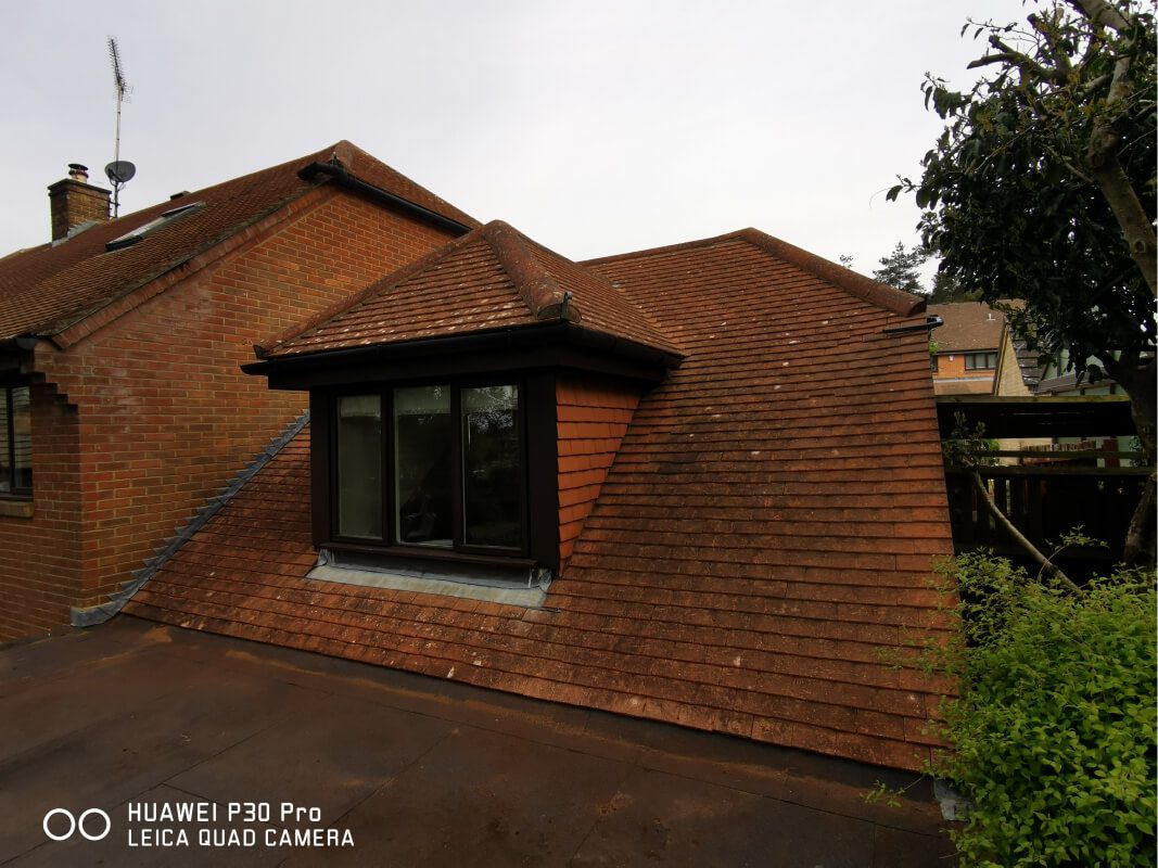 Dirty red shingle roof in need of cleaning