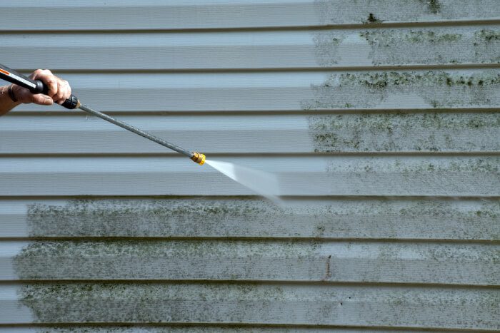 White external wall being cleaned via powerwash