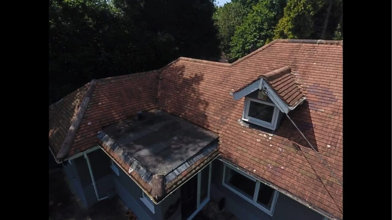 Uneven red tiled roof post soft wash clean with gutters