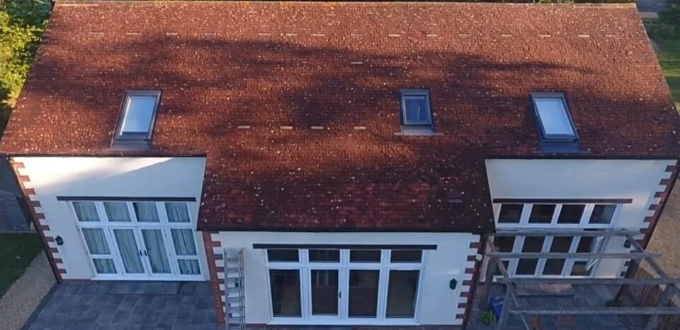 White home with red tile roof in need of cleaning the moss