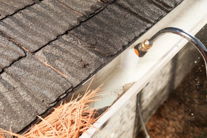 Dirty white gutters being cleaned via specialist hose